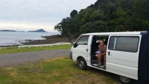 Clair sitting in Shitty parked at the Long Bay Motor Camp, Town of Coromandel.